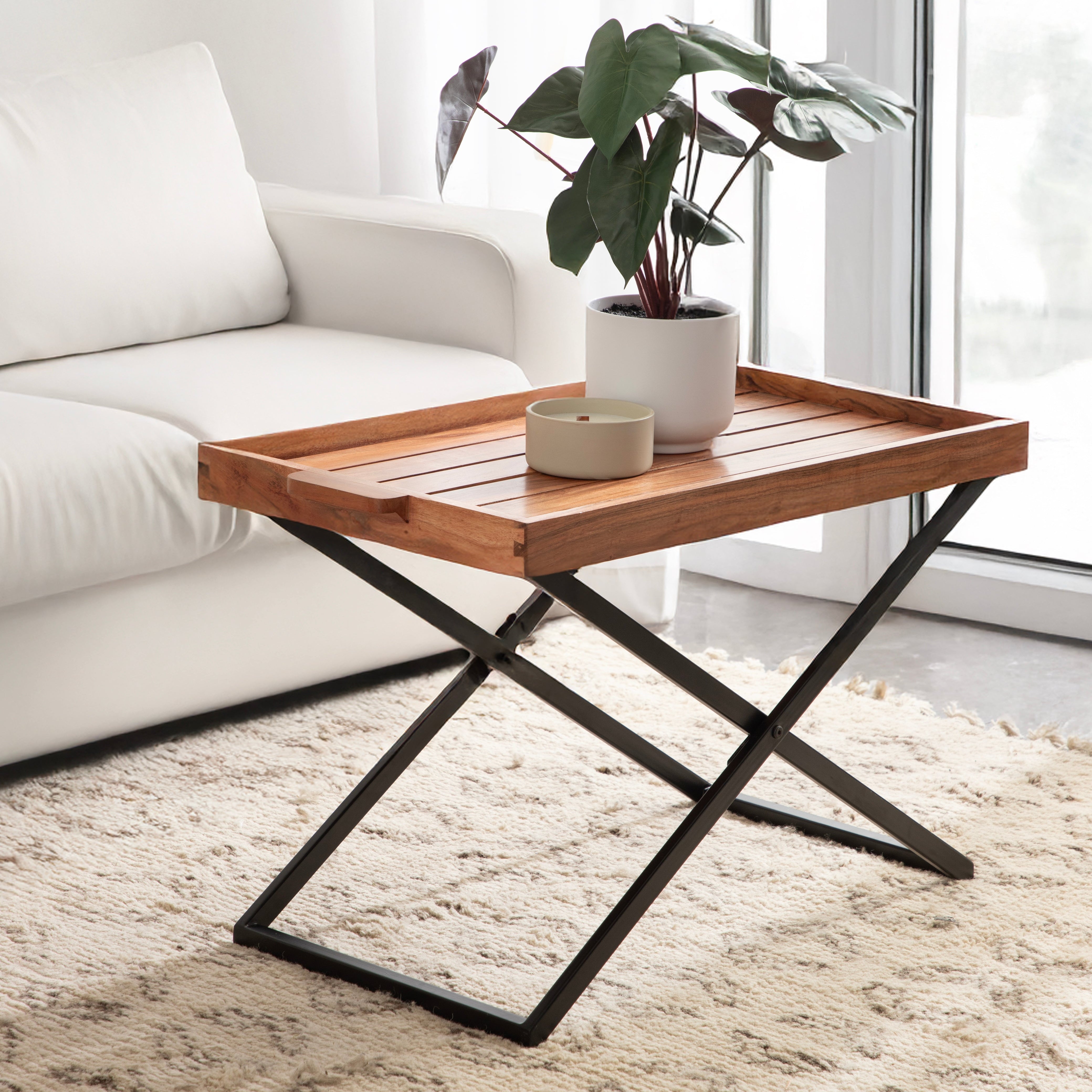 Wooden coffee table with a plant and decorative items in a living room setting.