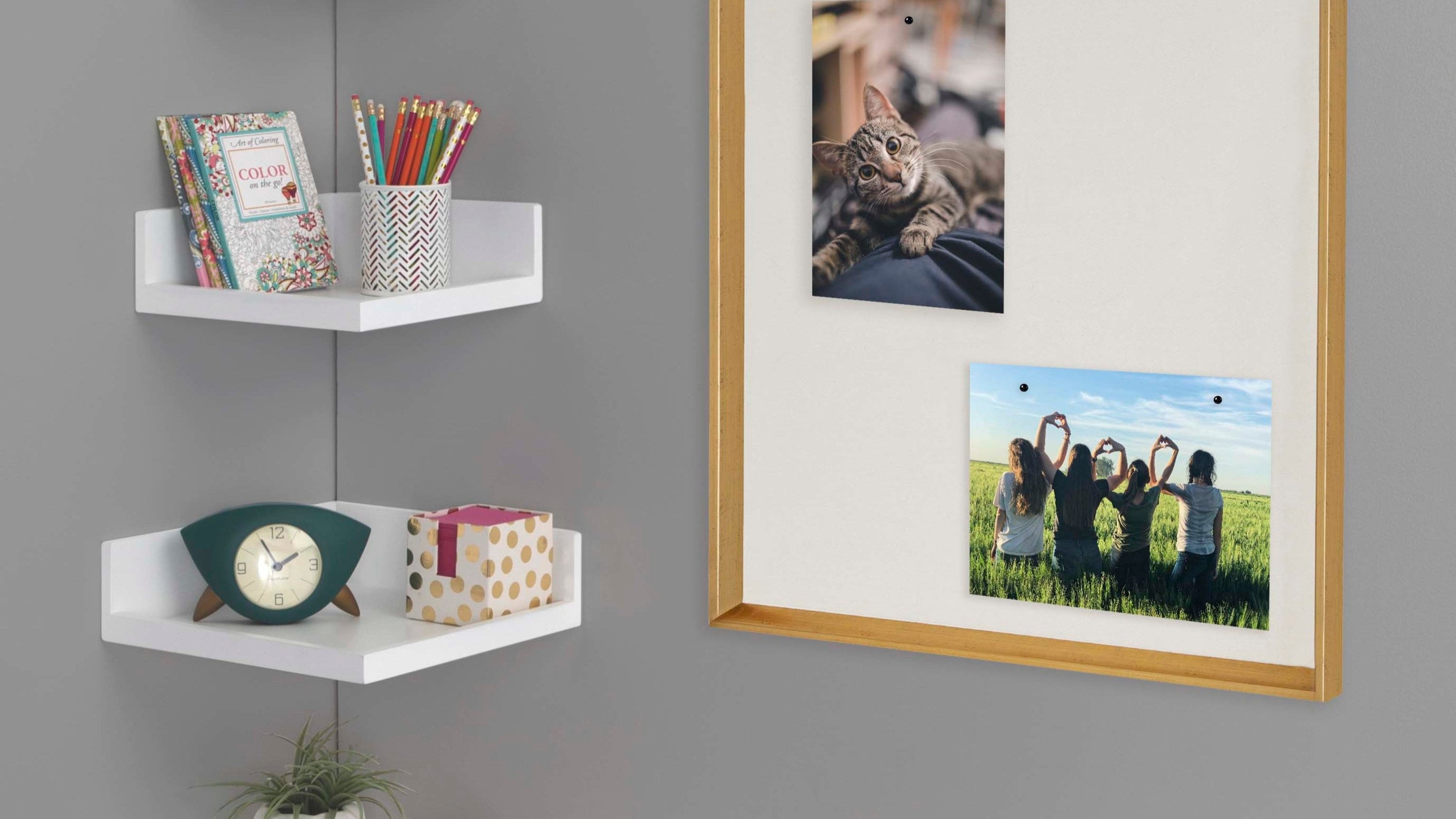 White corner shelves with decorative items against a gray wall with framed pictures.