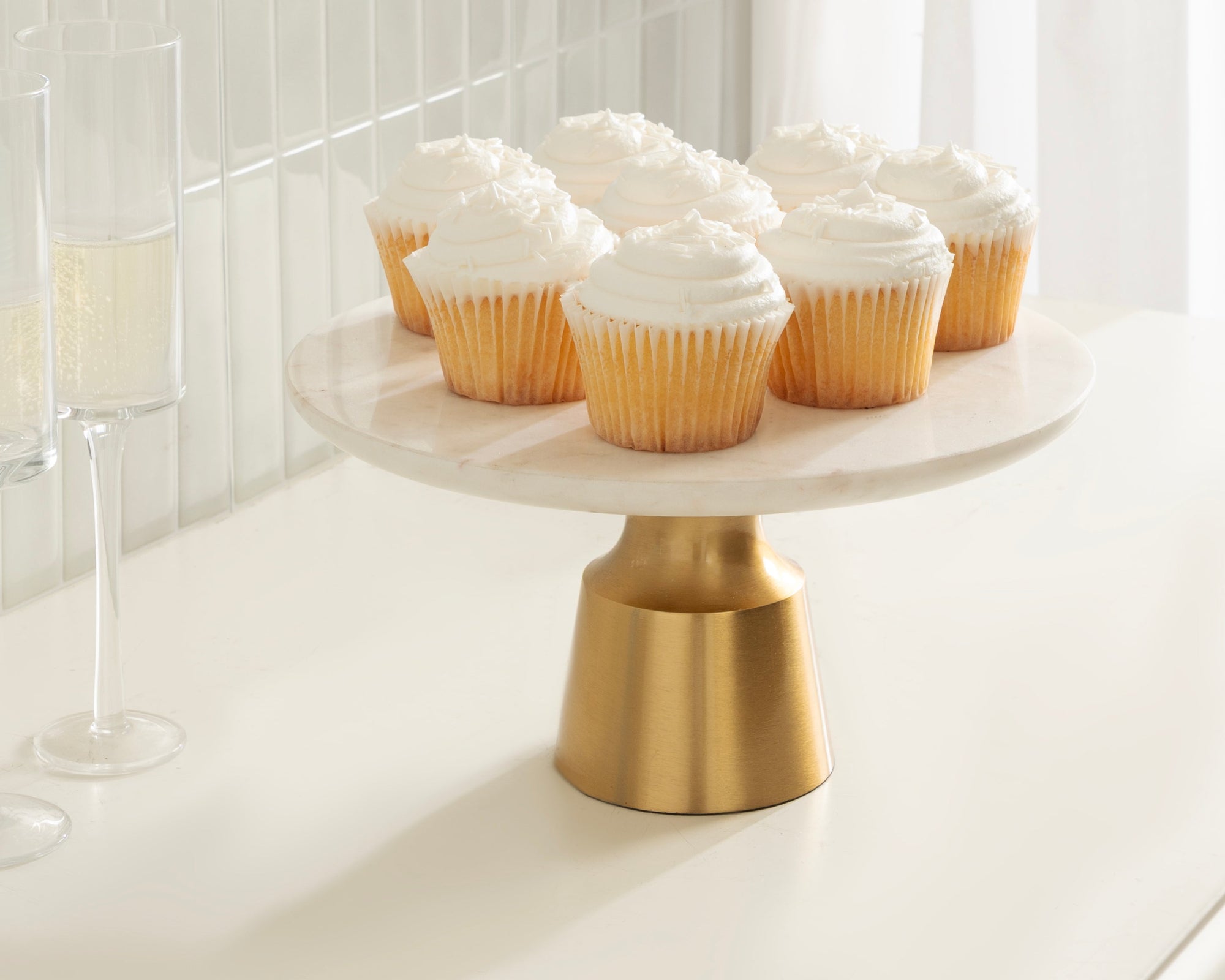 Cupcakes on a white cake stand with gold base in a minimalistic setting