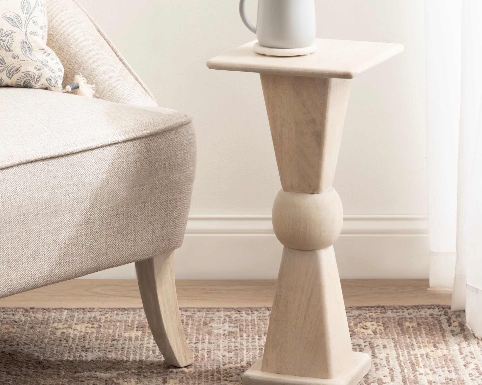 White mug on a small wooden side table in a living room.